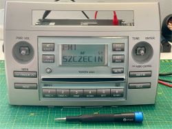 Zbliżenie na panel radia samochodowego Toyota W58810 na macie serwisowej z narzędziem iFixit.