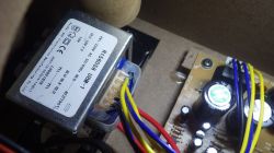 Elektronische Bauteile im Gehäuse Ansicht von elektronischen Bauteilen in einem Gehäuse, einschließlich eines Transformators mit Beschriftungen und Kabeln.