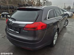 A grey Opel Insignia station wagon parked on a wet lot, rear left view.