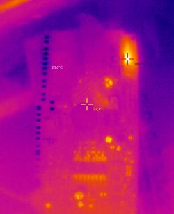 Obraz termowizyjny z dwoma świecącymi rezystorami SMD na płytce elektronicznej.