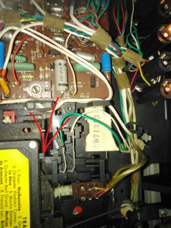 Wnętrze urządzenia elektronicznego z widoczną płytką drukowaną i przewodami.