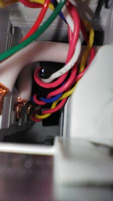 Interior of an electrical device with visible colored wires (red, yellow, green, blue, white), close-up of wiring.