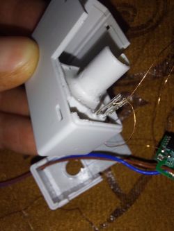 Close-up of an opened white plastic device casing with wires and a small circuit board