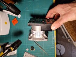 Hand holding an electronic module connected to a metal valve