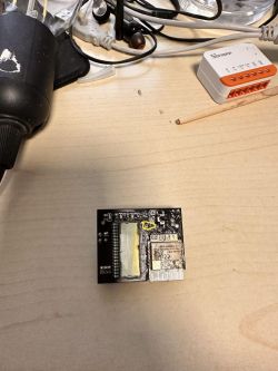 Printed circuit board on a desk with a missing capacitor marked with a yellow symbol.