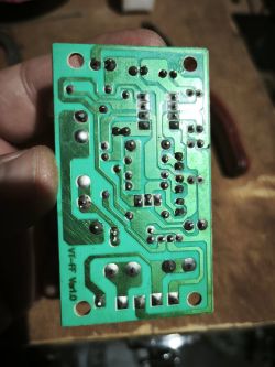 Spód zielonej płytki PCB z widocznymi ścieżkami miedzi i punktami lutowniczymi, trzymanej w dłoni