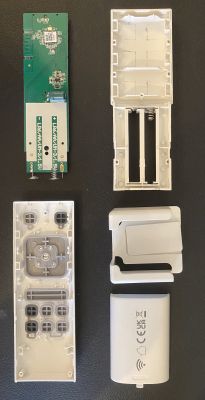 Disassembled remote control with visible internal components and casing on a black background.