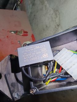 Kondensator oznaczony jako CBB61 SH, 450V AC/50Hz, 1,5µF ±5%, na tle metalowej obudowy z kablami.