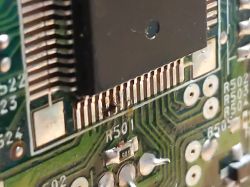 Zbliżenie na uszkodzoną płytkę drukowaną z przepaloną ścieżką.