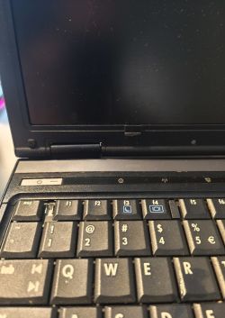 Zbliżenie klawiatury i ekranu laptopa HP Compaq 6910p z widocznym przyciskiem zasilania.
