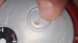 Zbliżenie na element plastikowy z otworem i metalowym stykiem w zabawce jeździku.