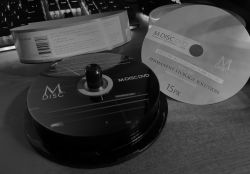 Stos płyt M-DISC DVD z opakowaniem oznaczonym jako 15PK na biurku