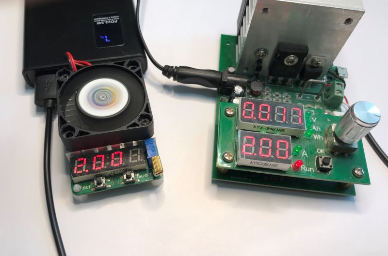 Power bank connected to load tester with voltage and current digital displays