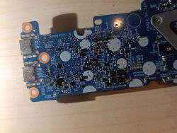 Close-up of a blue PCB with two USB ports on the left edge, on a wooden surface