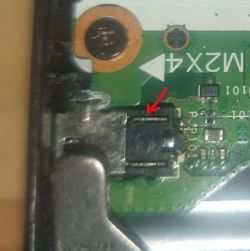 Zbliżenie płytki PCB z czarnym złączem i czerwoną strzałką wskazującą pin