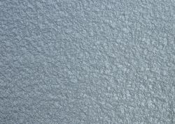 Zbliżenie na powierzchnię pokrytą szarą farbą o pomarszczonej teksturze.