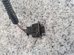 Close-up of a car electrical connector with wires on a countertop surface.