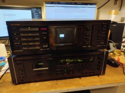 Dwa magnetofony Nakamichi RX-505E i CR-7E ustawione jeden na drugim na biurku