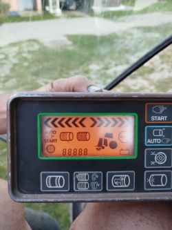 Panel sterujący prasy John Deere 590 z wieloma ikonami i zapalonymi kontrolkami.
