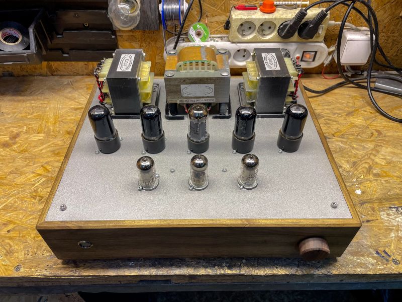 DIY Tube Amplifier on Workshop Bench Tube amplifier with various tubes and transformers on a wooden and metal enclosure.
