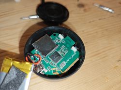 Dismantled small electronic device showing circuit board and battery