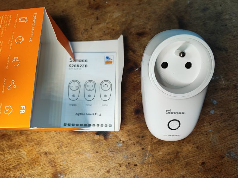 Otwarta skrzynka z inteligentną wtyczką Sonoff S26R2ZB i instrukcją obsługi.