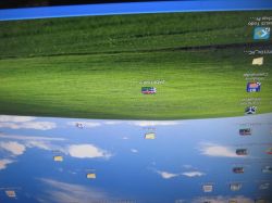 Odwrócony ekran pulpitu Windows z ikonami i zielono-niebieską tapetą