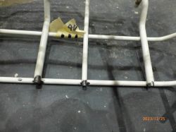 Fragment kosza do zmywarki z oznaczeniem numerowym i widocznymi śladami rdzy.