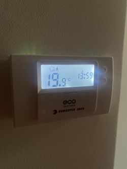 Termostat ścienny pokazujący temperaturę 19,9 stopni Celsjusza.