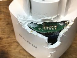 Damaged plastic device casing with visible interior and PCB.