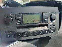 Oryginalne radio CD Toyota Corolla Verso E13 z wyświetlaczem LCD pokazującym zużycie paliwa, przyciski sterujące i pokrętła.