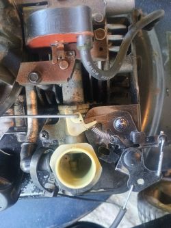 Widok silnika kosiarki Briggs & Stratton Quattro 40 z wyraźnie widocznym systemem przepustnicy i sprężynką.