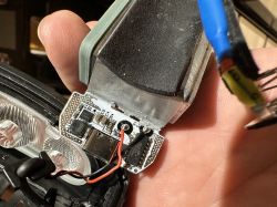 Zbliżenie na wewnętrzne elementy lampki rowerowej z płytką PCB i portem USB-C.