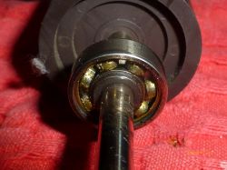 Zbliżenie na wałek wirnika z widocznym łożyskiem i resztkami smaru.