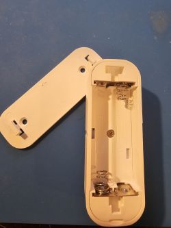 Inside of AUBESS Door Sensor Opened white door sensor case with visible battery springs inside.