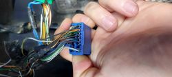 Niebieska kostka elektryczna z wieloma kolorowymi przewodami w ręce osoby.
