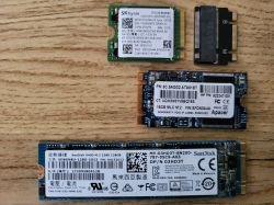 Cztery moduły M.2 SSD różnych rozmiarów i typów leżące na drewnianej powierzchni