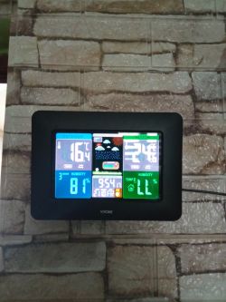 Digital weather station on the wall displaying temperature, humidity, and time.