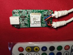 LED controller on a red fabric background with wires and a remote control.