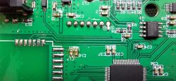 Close-up of an Electronic Device's PCB Close-up of a green PCB with various components, visible traces, and electronic elements.