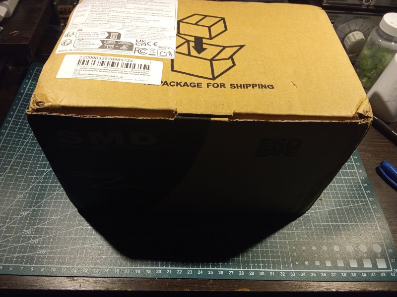 Kartonowe pudełko z etykietą i nadrukiem „PACKAGE FOR SHIPPING” na macie do cięcia.