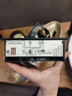 Naklejka ze schematem podłączeń na obudowie sterownika kotła trzymanego w dłoni