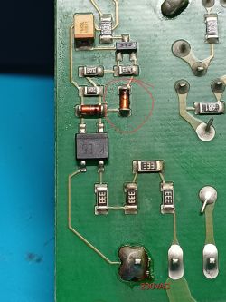Przyczerniony element elektroniczny zaznaczony na zielonej płytce PCB przy napięciu 230VAC
