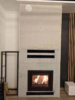 Fireplace with Skamol/Varmsen paneling, featuring new ventilation grilles.