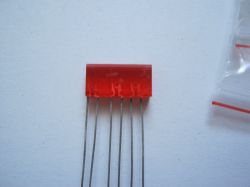 Czerwony element z pięcioma metalowymi końcówkami na białym tle.