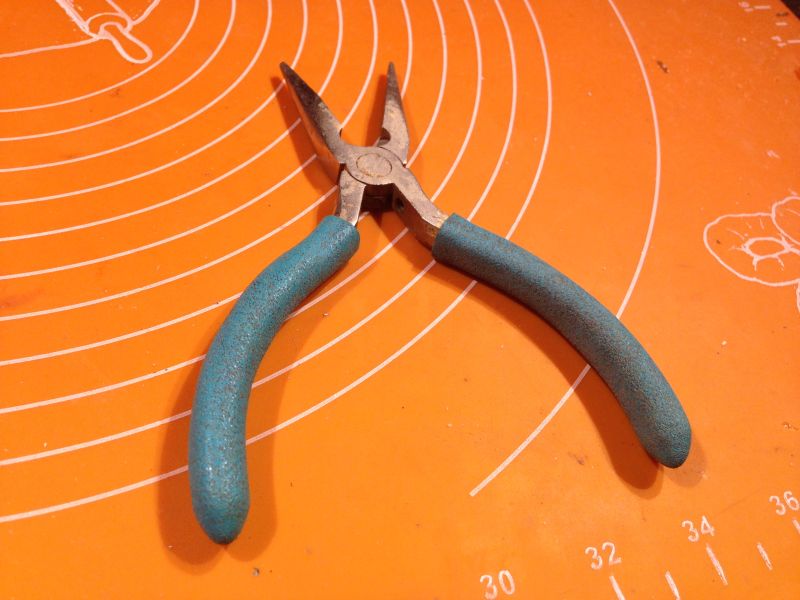 Zużyte kombinerki z zielonymi uchwytami na pomarańczowym tle