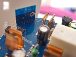 Close-up of a blue PCB with capacitors, connectors, and TX/RX labeled module