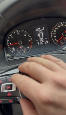 Wskaźniki VW Caddy z ręką naciskającą przycisk tempomatu na kierownicy