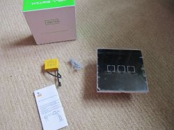 Touch wall switch kit: three-button panel, yellow module, screws, manual, and box.