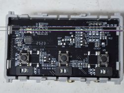 Close-up of a PCB with push buttons and electronic components in a gray casing.